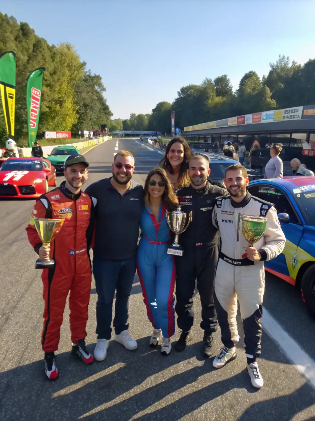 A diverse group of members participating in a motorsport event, cheering and supporting each other, emphasizing the inclusive community aspect of ATLANTIC MOTOR SPORT 17.